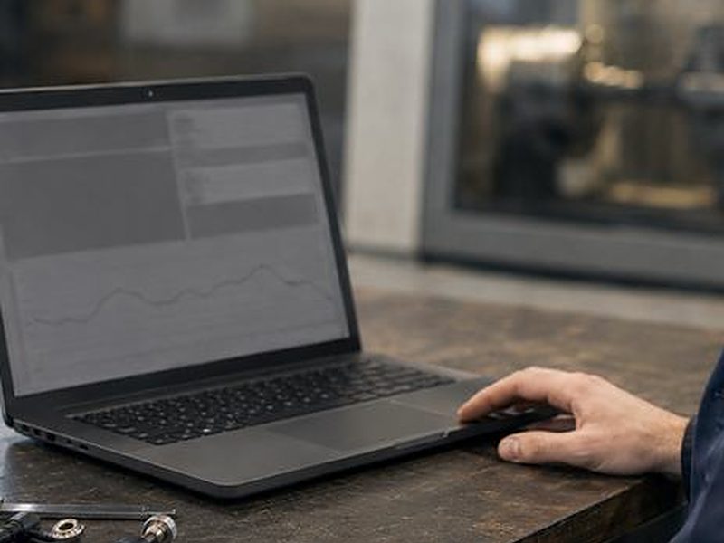 Laptop an einer Werkbank vor einer Werkzeugmaschine